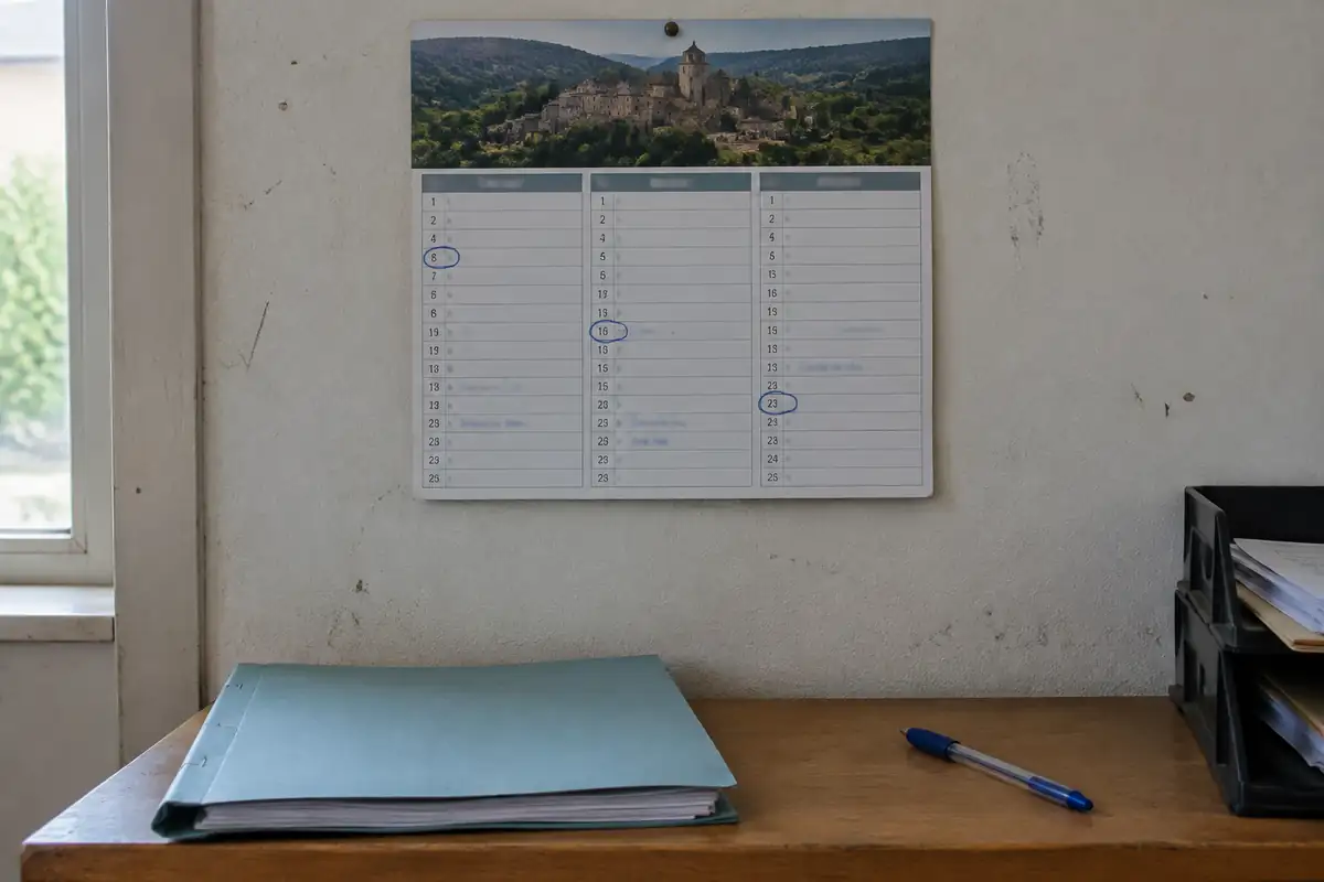 Calendrier mural avec trois dates entourées au stylo, au-dessus d'un dossier